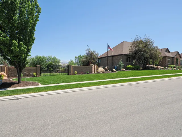 Expansive front lawn with mature trees and a decorative stone wall