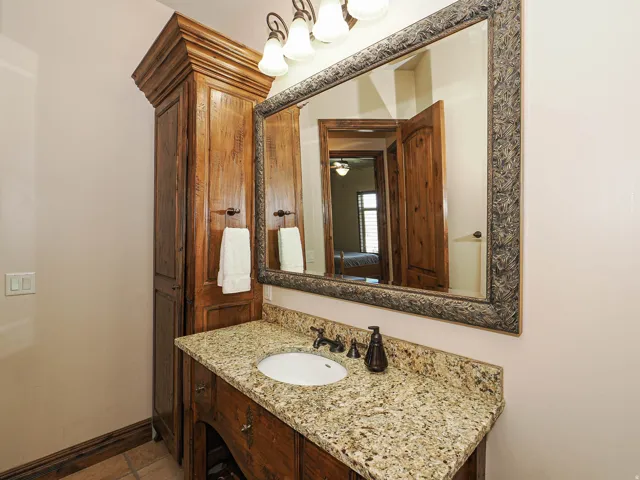 Bathroom vanity featuring a granite countertop, undermount sink, and dark bronze faucet