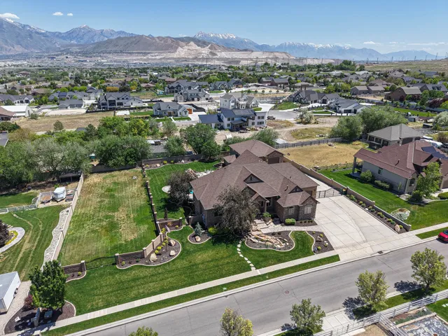 Spacious property featuring a large residence with a multi-gabled roof, extensive concrete driveway, and manicured front landscaping