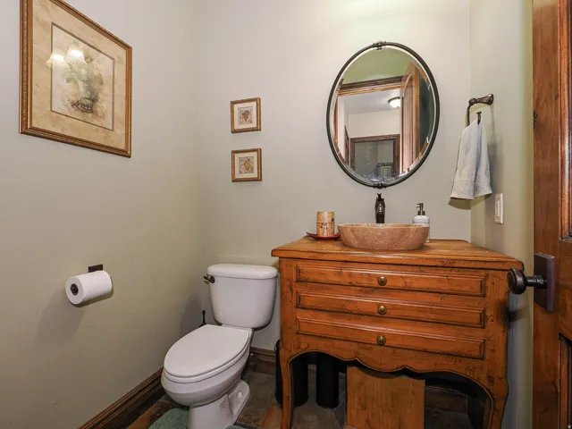 Powder room featuring a stone vessel sink, a distressed wood vanity, and a circular framed mirror