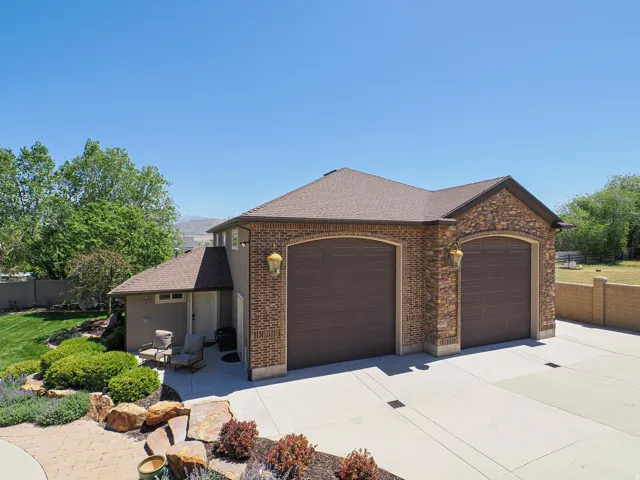 Two-car garage with arched doors, brick and stone facade, and sconce lighting