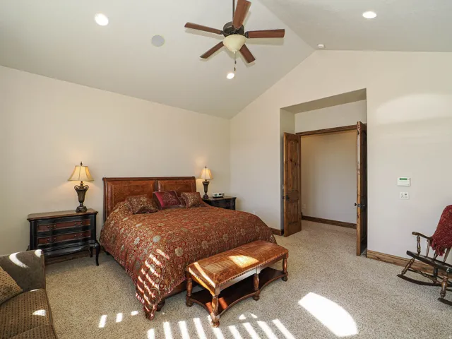 Vaulted ceiling room featuring a ceiling fan with integrated lighting, recessed lighting, carpet flooring, and double wood-paneled doors
