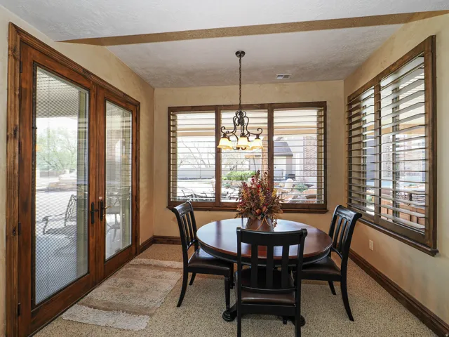Dining area featuring French doors with wood trim, plantation shutters, and a chandelier