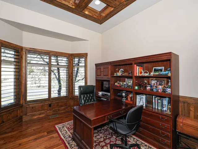 Room featuring wood-finish flooring, a tray ceiling with wood beam accents, and extensive built-in cabinetry