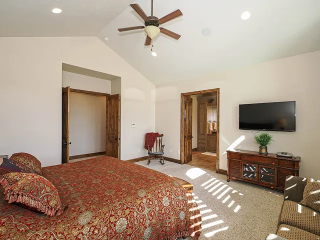 Vaulted ceiling room featuring a ceiling fan, recessed lighting, and rich wood-finish doors