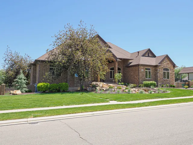 Stone and brick facade residence featuring a multi-gabled roofline, arched entry, mature landscaping, and an expansive lawn