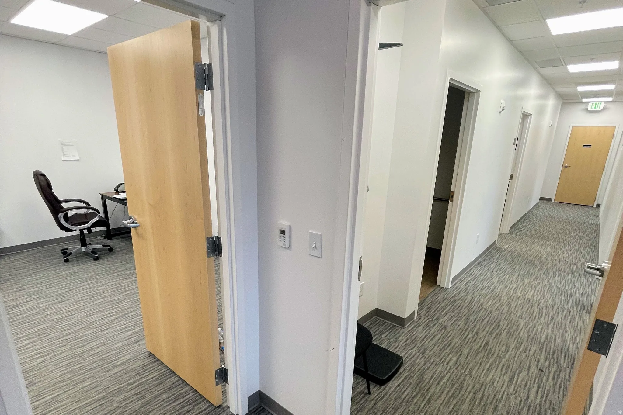 Corridor with a paneled ceiling, dark carpet, and a desk