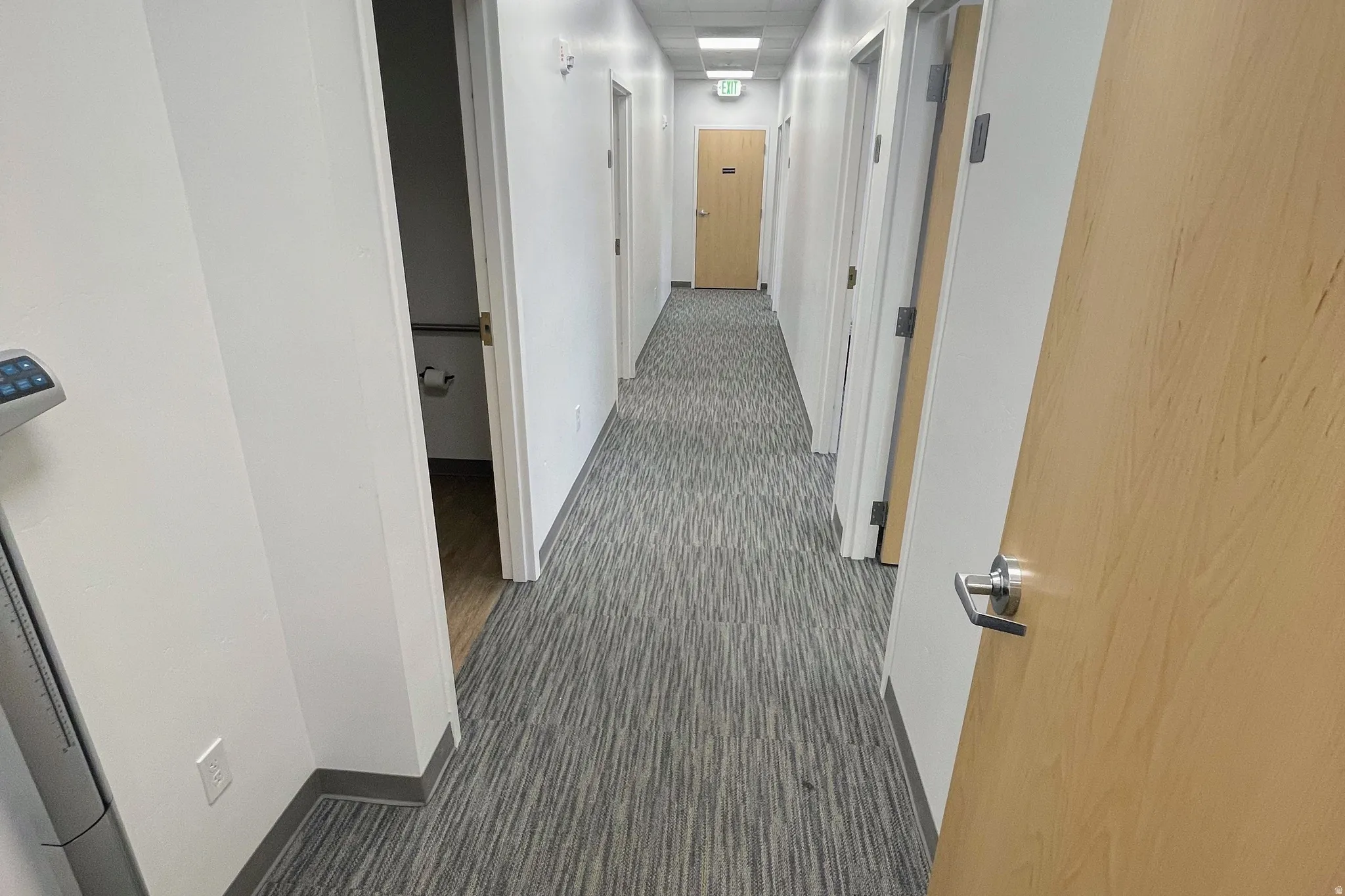 Corridor featuring baseboards and dark carpet
