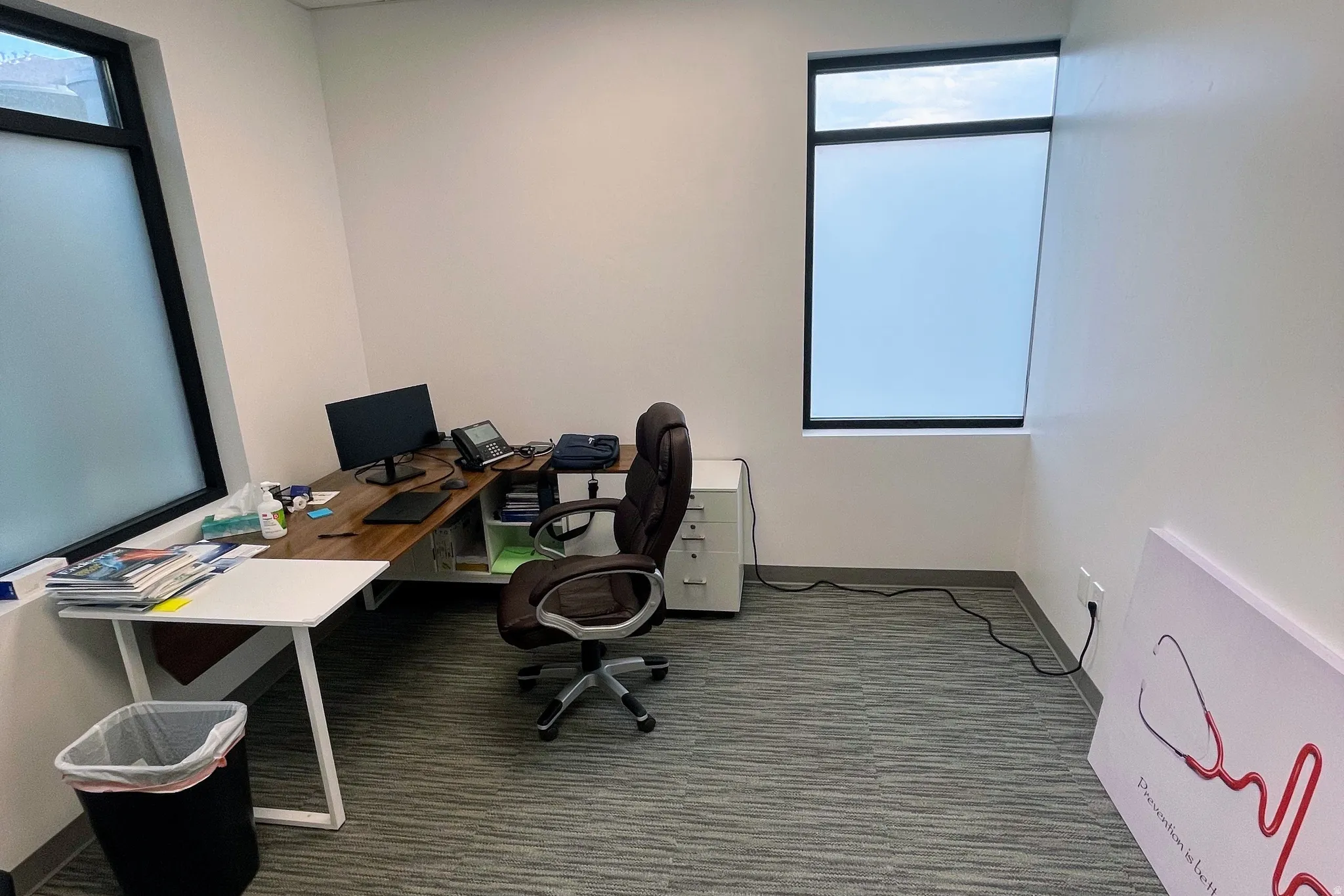 Office area featuring dark colored carpet and baseboards
