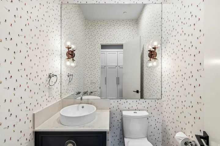 Half bathroom with vanity and wallpapered walls