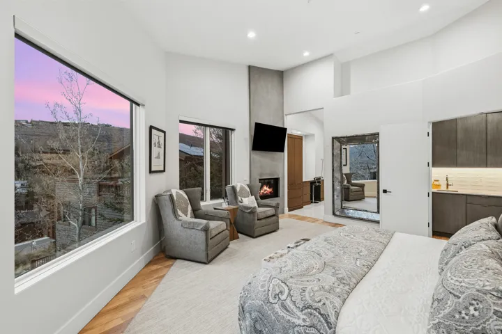 Bedroom featuring light wood-type flooring, a large fireplace, a high ceiling, recessed lighting, and ensuite bath