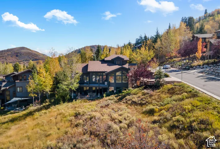 Multi-story mountain residence featuring dark-toned wood siding, expansive glass windows, an attached balcony, and stone exterior accents