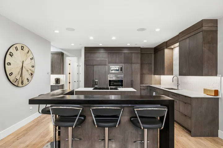 Kitchen with a kitchen island, a kitchen bar, light wood-style floors, modern cabinets, and recessed lighting