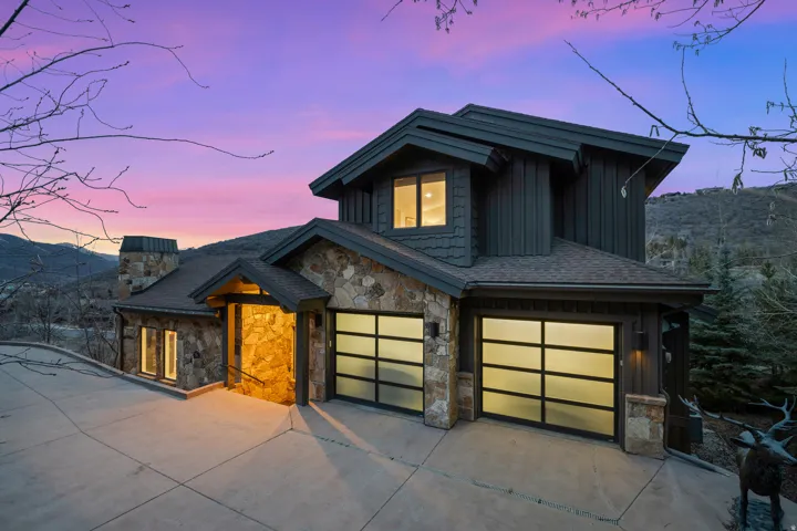 Contemporary house featuring board and batten siding, concrete driveway, stone siding, and an attached garage
