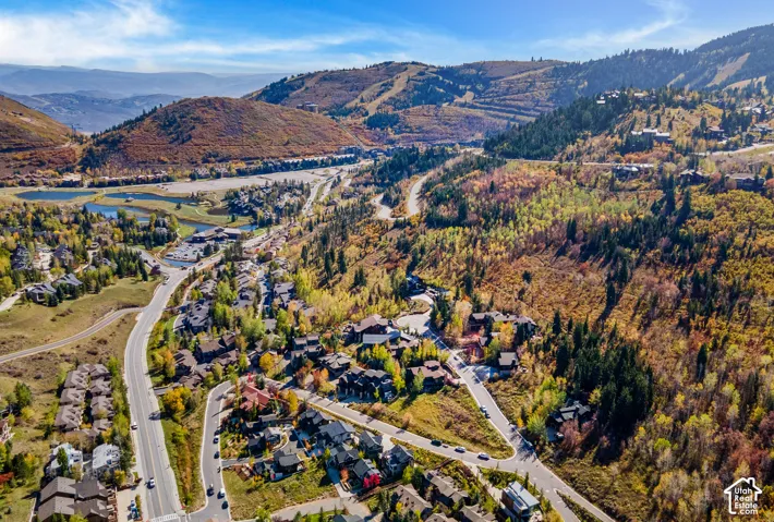 Aerial perspective showcasing expansive mountain terrain, sweeping ridgeline topography, dense forest clusters, and natural seasonal vegetation