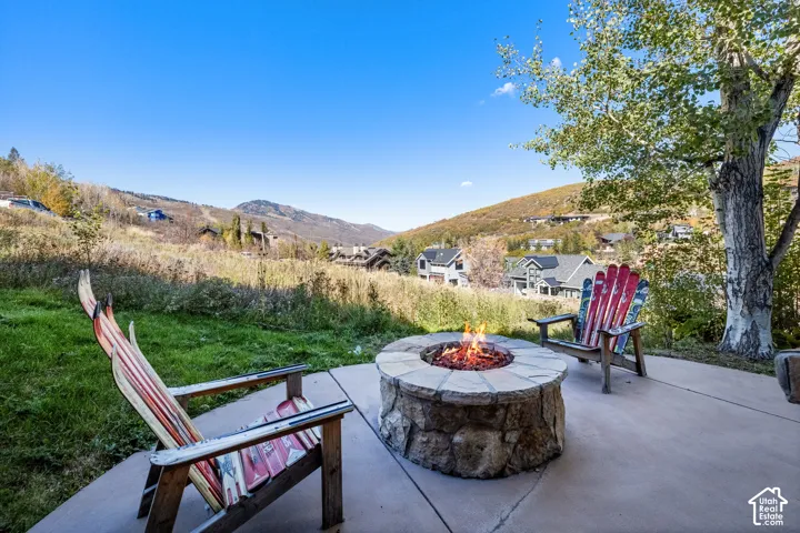 Concrete patio featuring a circular stone fire pit and a mountain backdrop