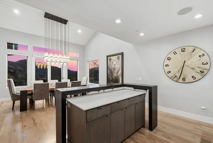 Kitchen featuring suspended lighting, dark wood finish cabinetry, light wood-type flooring, a center island, and vaulted ceiling