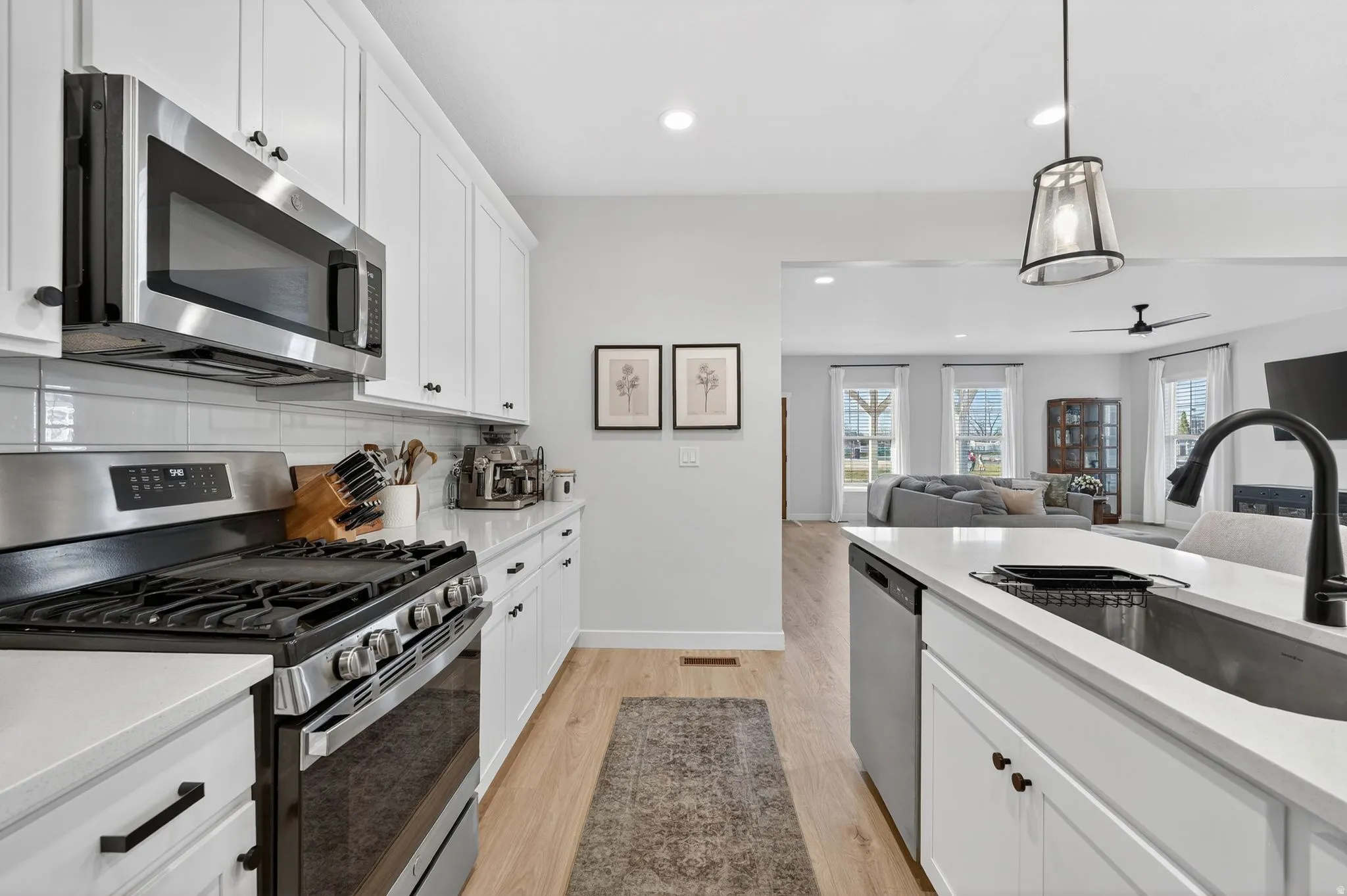 Kitchen with stainless steel appliances, white cabinets, and light stone counters