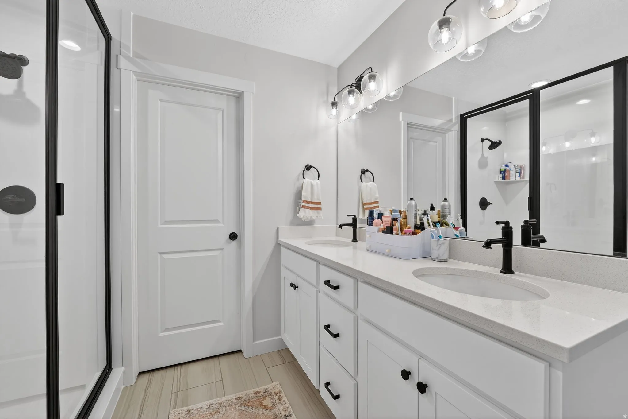 Full bath featuring a stall shower, double vanity, and a textured ceiling