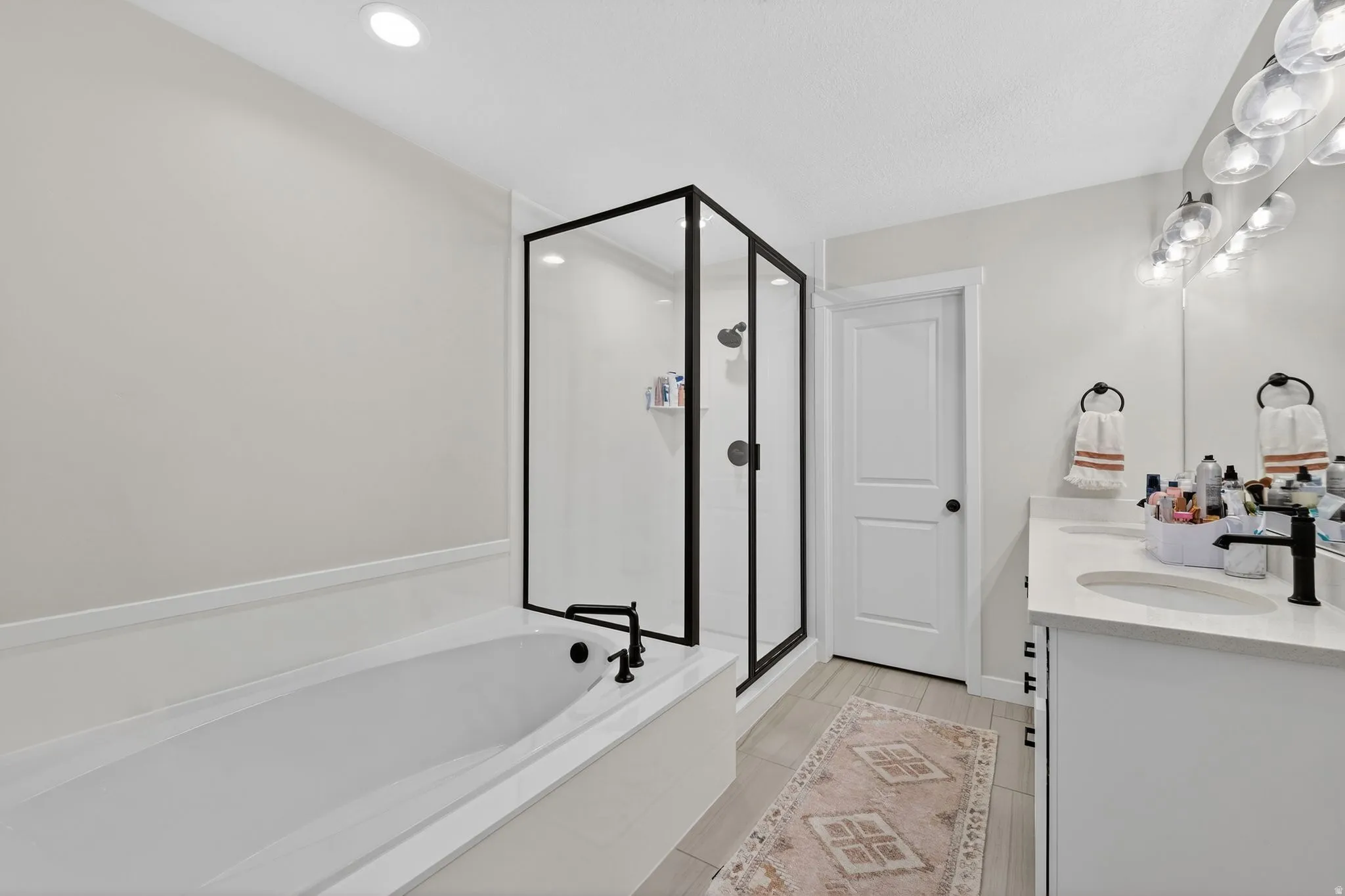 Full bath with double vanity, a garden tub, and a stall shower