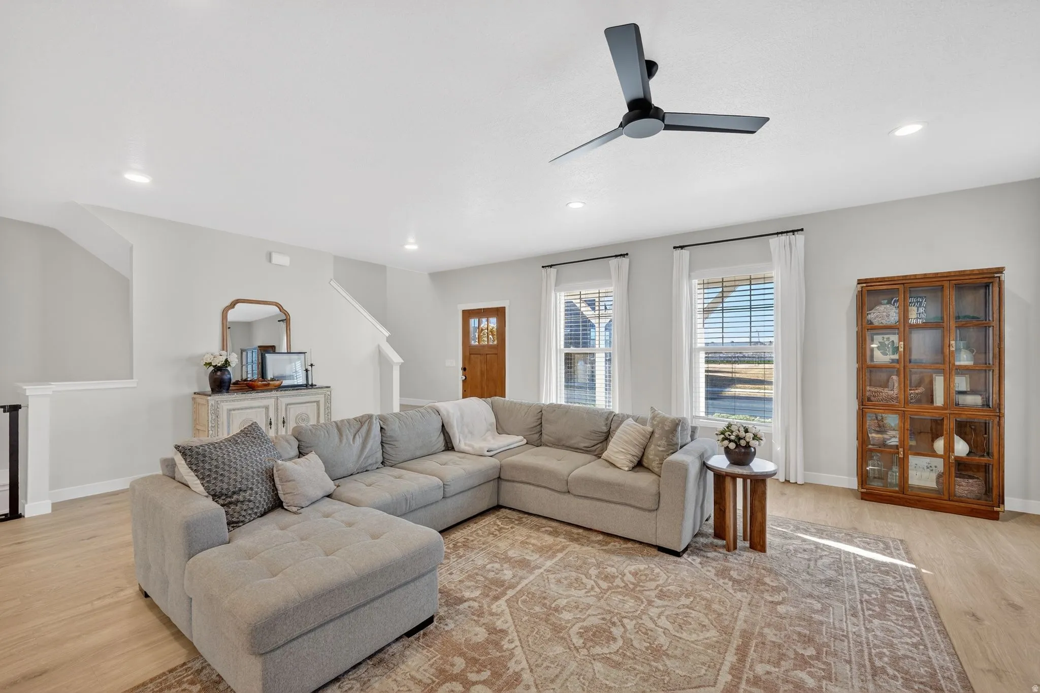 Living room with light wood-style floors, ceiling fan, and recessed lighting