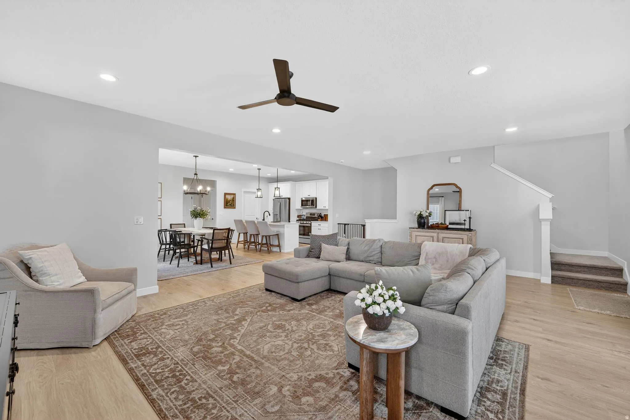 Living area with ceiling fan, light wood-style floors, and suspended lighting