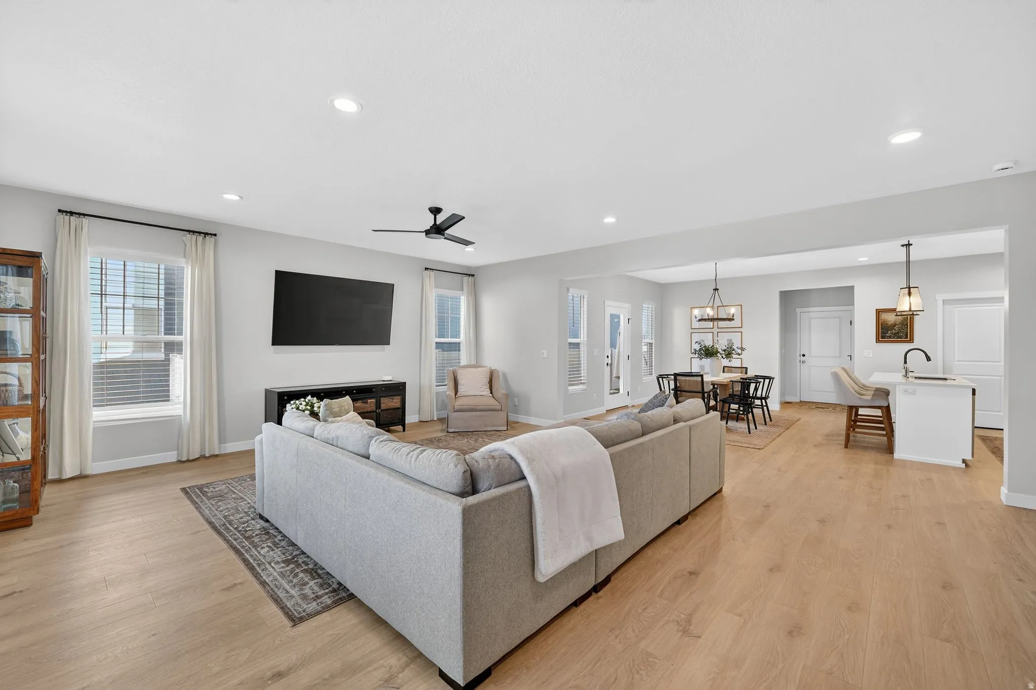 Living room featuring ceiling fan, light wood-style floors, and a chandelier