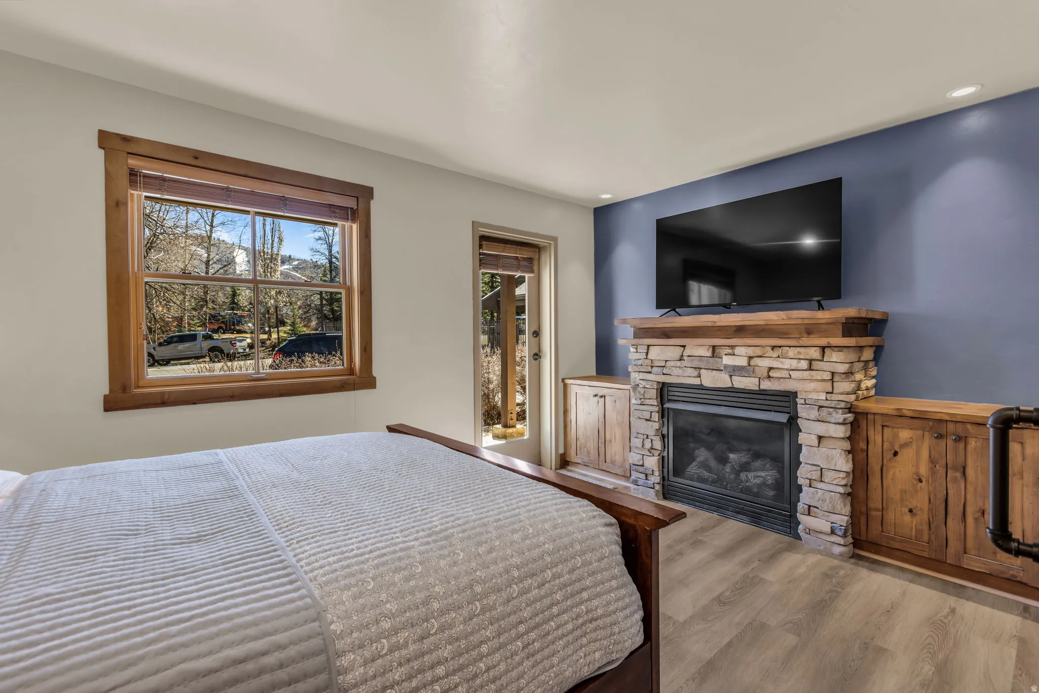 Bedroom with wood finished floors and a stone fireplace