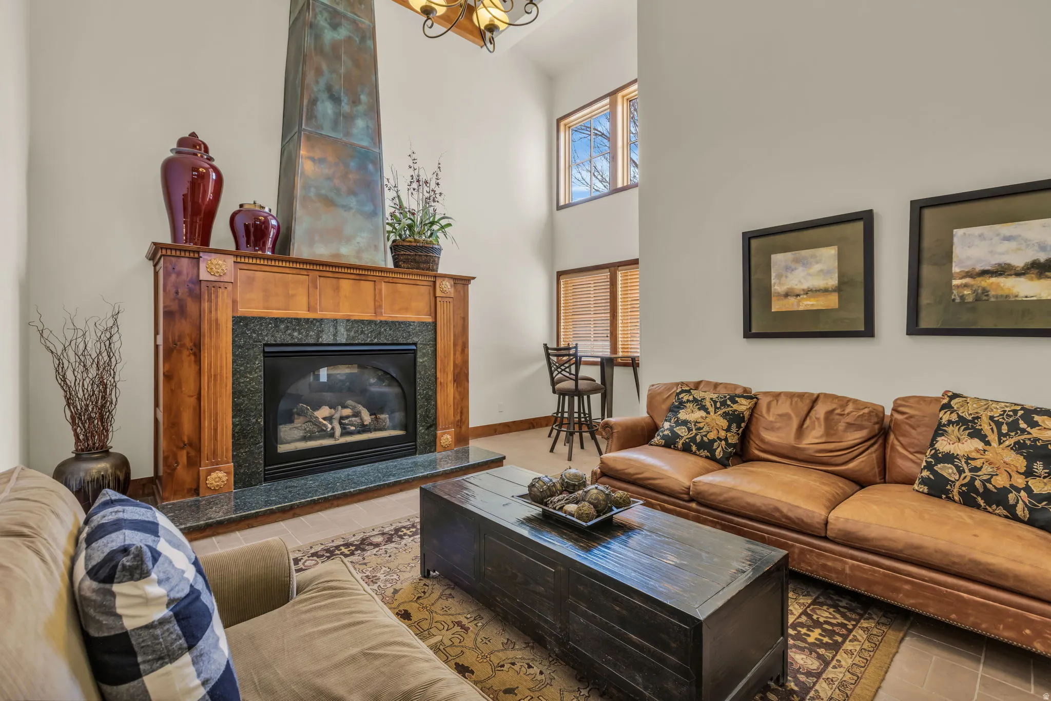 Living room with a high ceiling, a premium fireplace, and light tile patterned floors