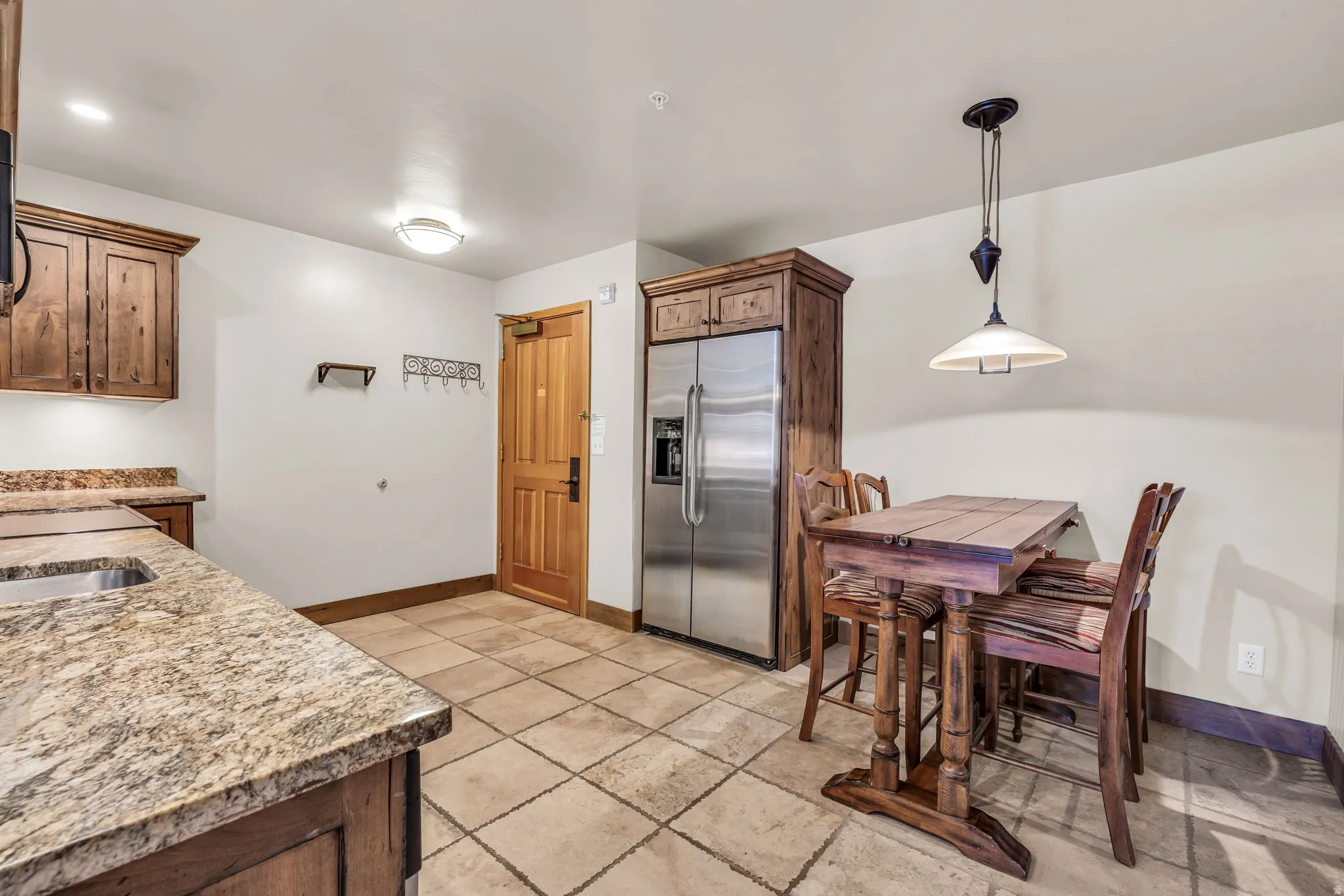 Kitchen with stainless steel built in refrigerator, light stone countertops, and hanging light fixtures