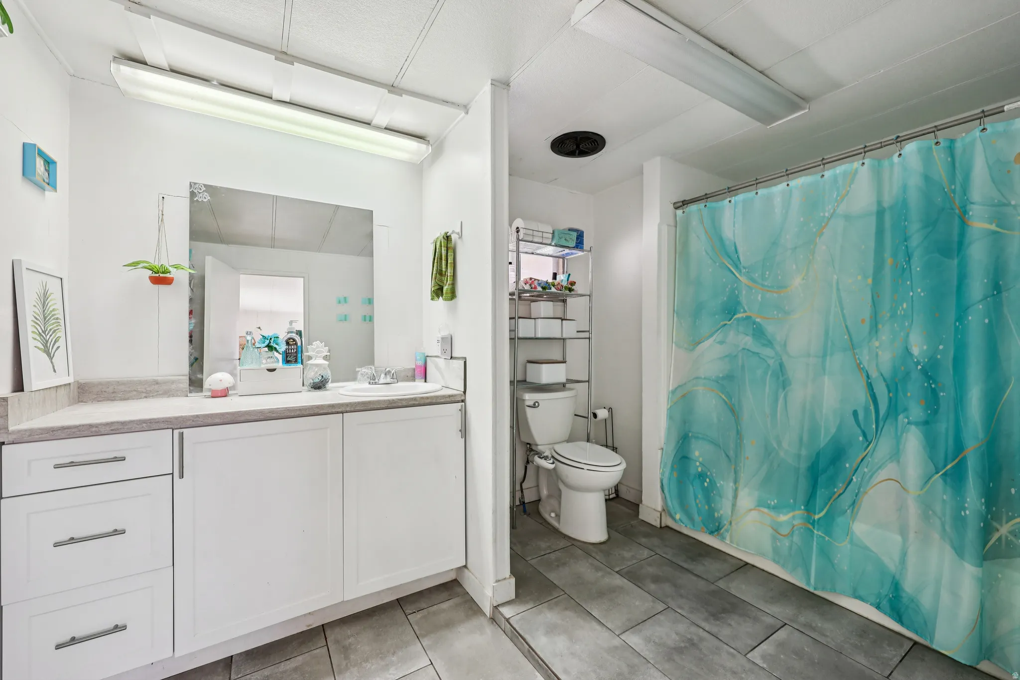 Bathroom featuring vanity, light tile patterned flooring, and shower / bathtub combination with curtain