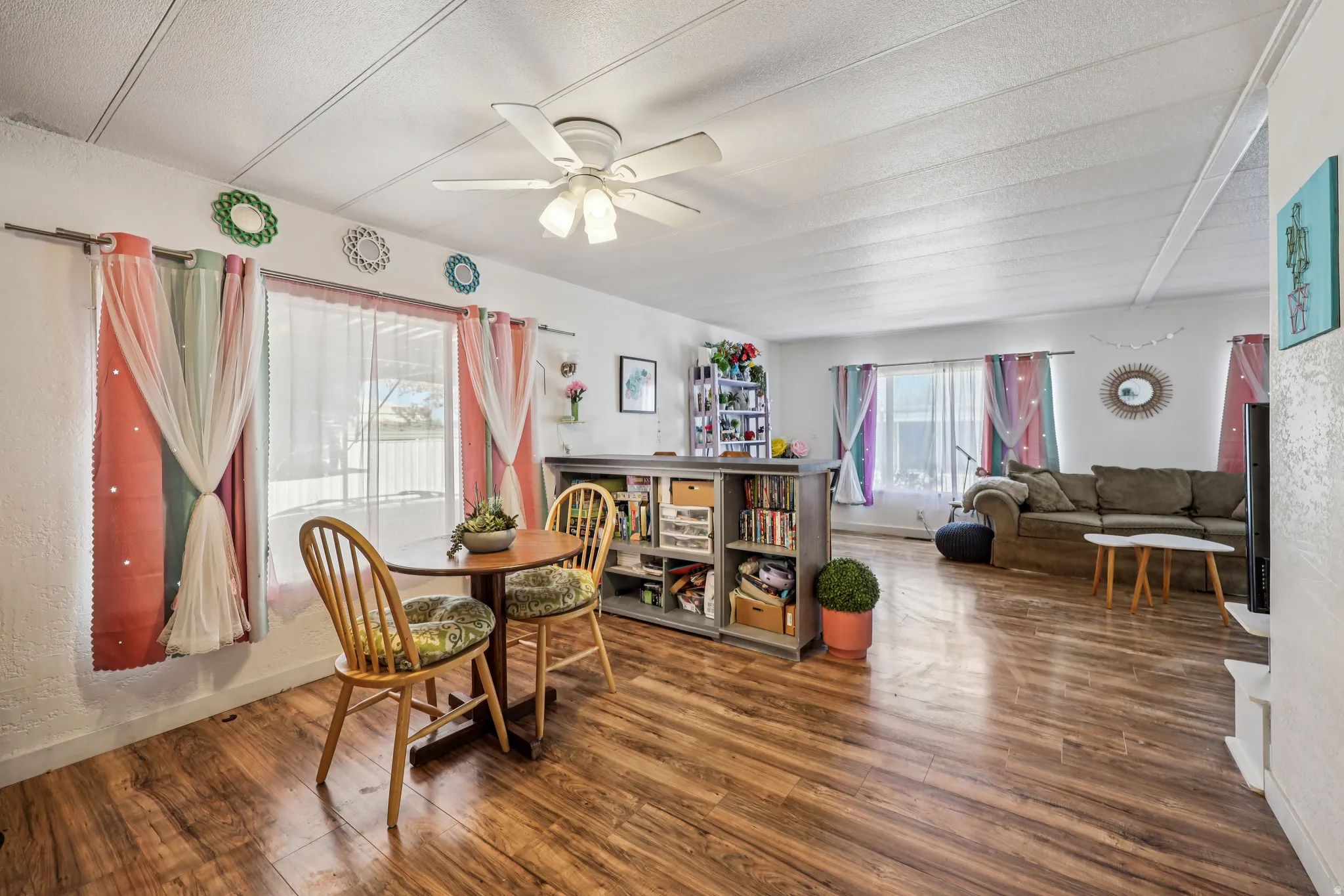 Dining space featuring a ceiling fan, wood finished floors, and a textured ceiling