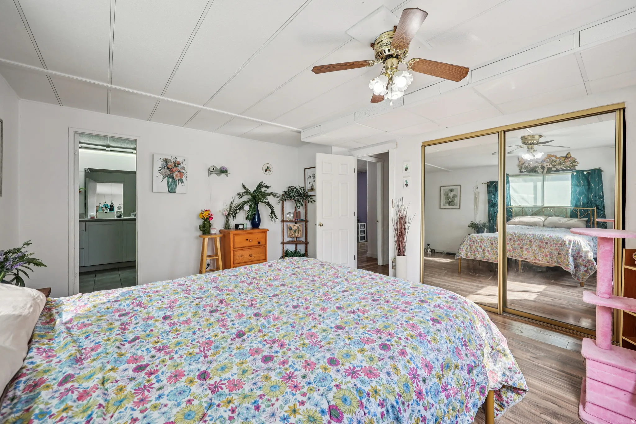 Bedroom with ceiling fan, dark wood-style floors, a closet, and ensuite bath