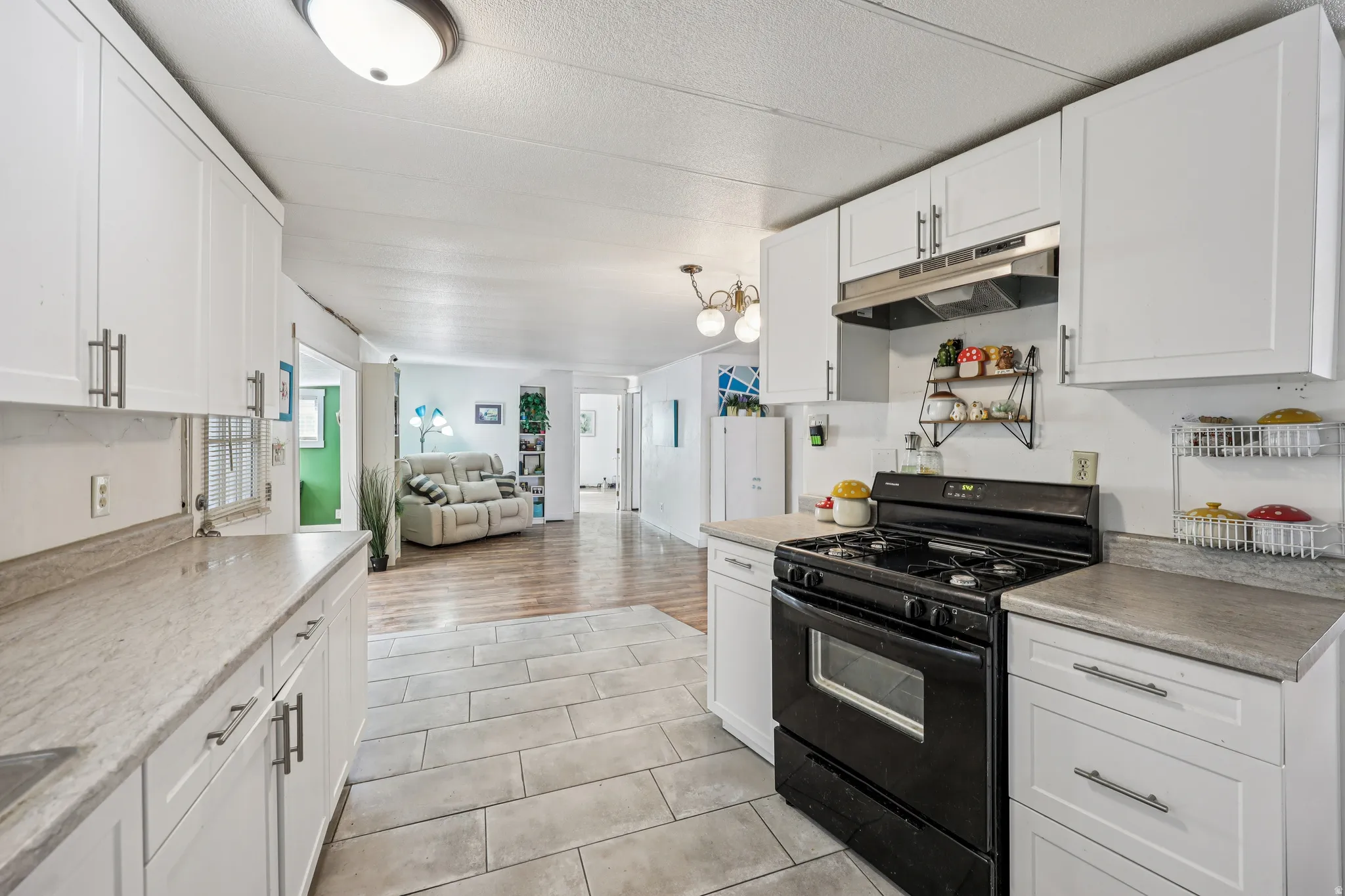Kitchen featuring gas stove, white cabinets, open floor plan, light countertops, and a textured ceiling