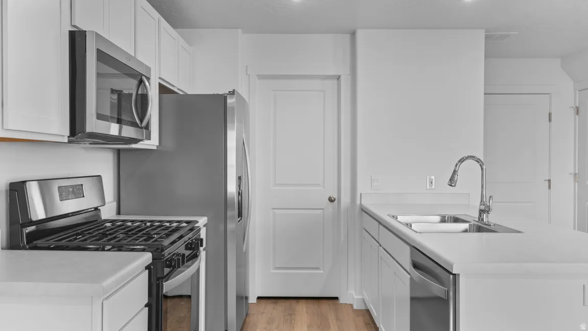 Kitchen featuring a peninsula, stainless steel appliances, light countertops, and light wood-style flooring