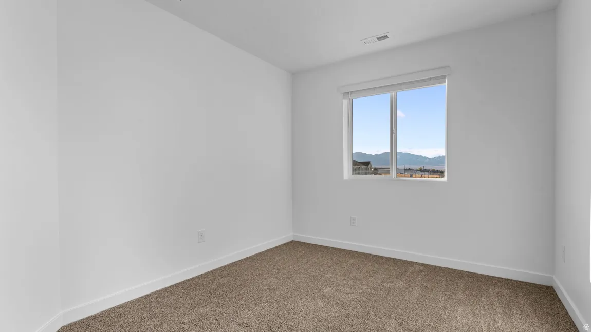 Carpeted empty room with baseboards and a mountain view