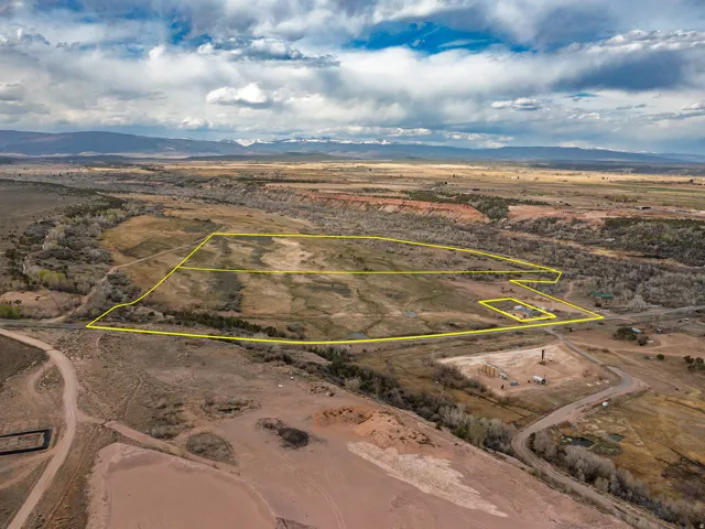 Aerial view of sparsely populated area with a mountainous background and property parcel outlined