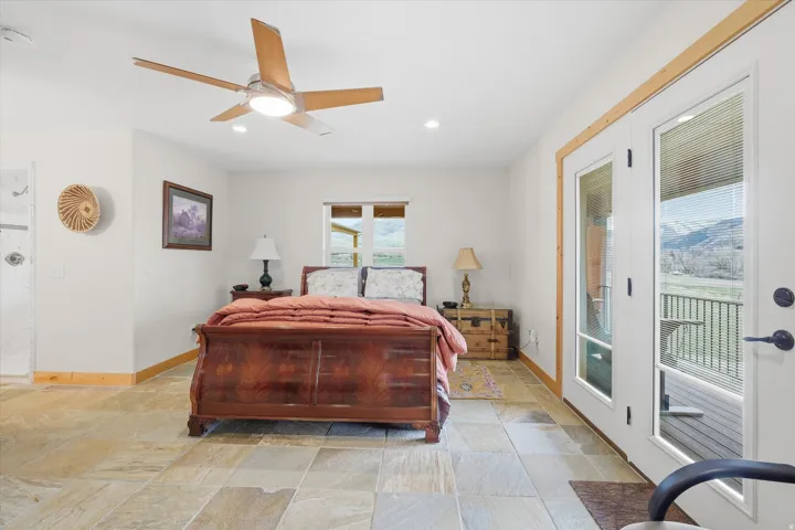 Bedroom with access to outside, ceiling fan, light stone finish flooring, and recessed lighting