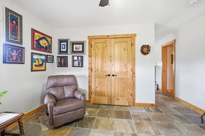 Living area featuring stone tile floors and ceiling fan