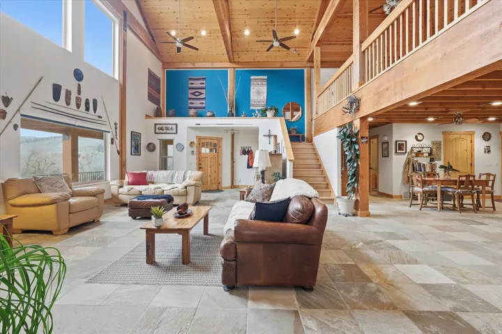 Living area featuring a high wooden beamed ceiling, ceiling fan, and recessed lighting