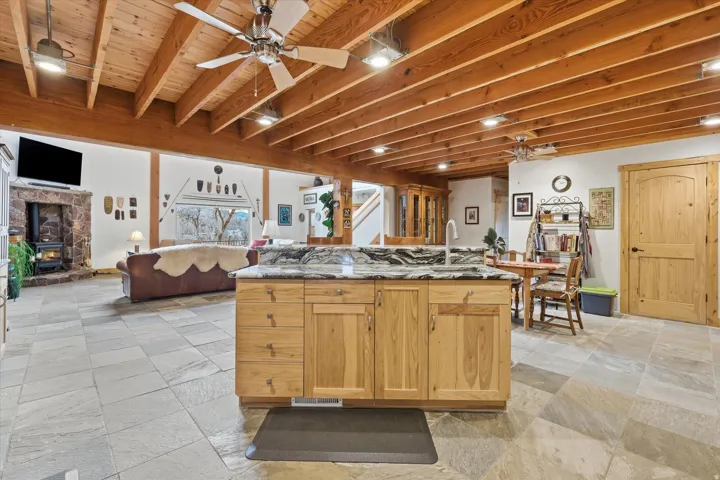 Kitchen featuring a ceiling fan, dark stone countertops, open floor plan, and a kitchen island with sink