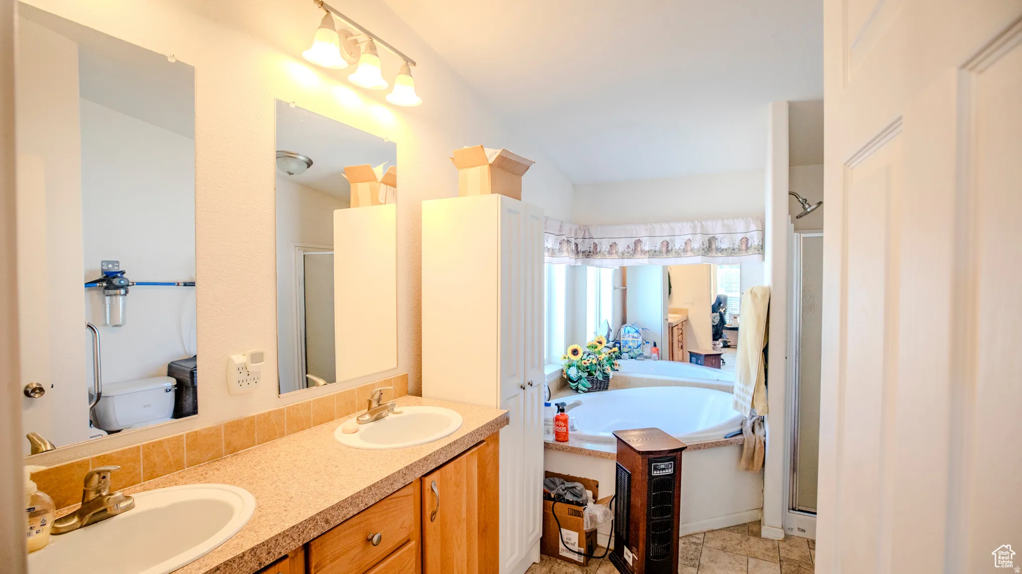 Full bath with double vanity, a stall shower, and a garden tub