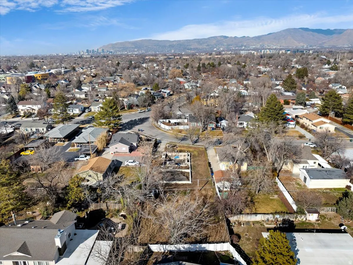 Aerial view of property and surrounding area featuring nearby suburban area and a mountainous background
