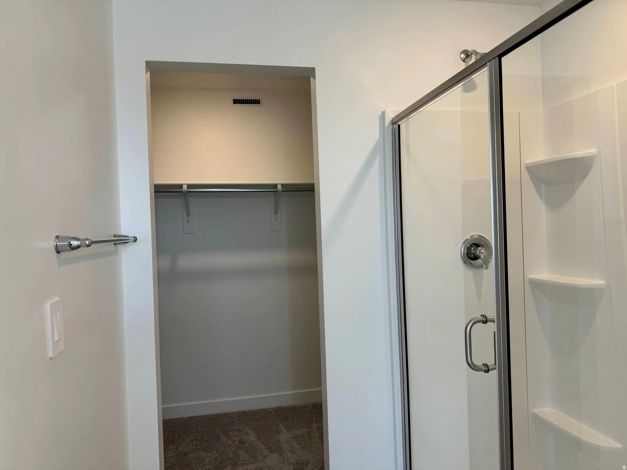 Full bathroom with a walk in closet, a stall shower, and dark colored carpet