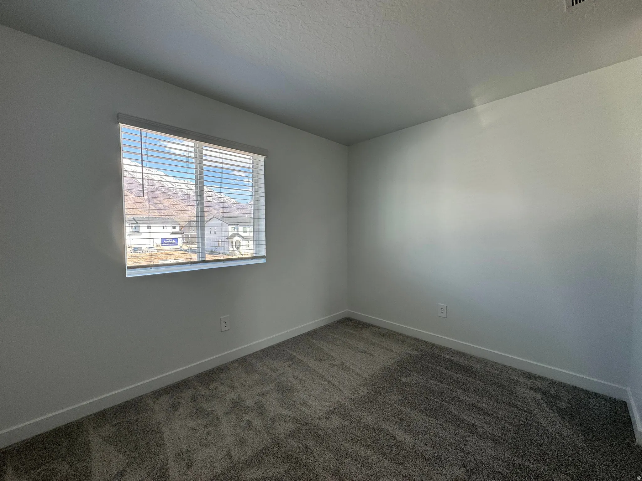 Unfurnished room featuring dark carpet and a textured ceiling