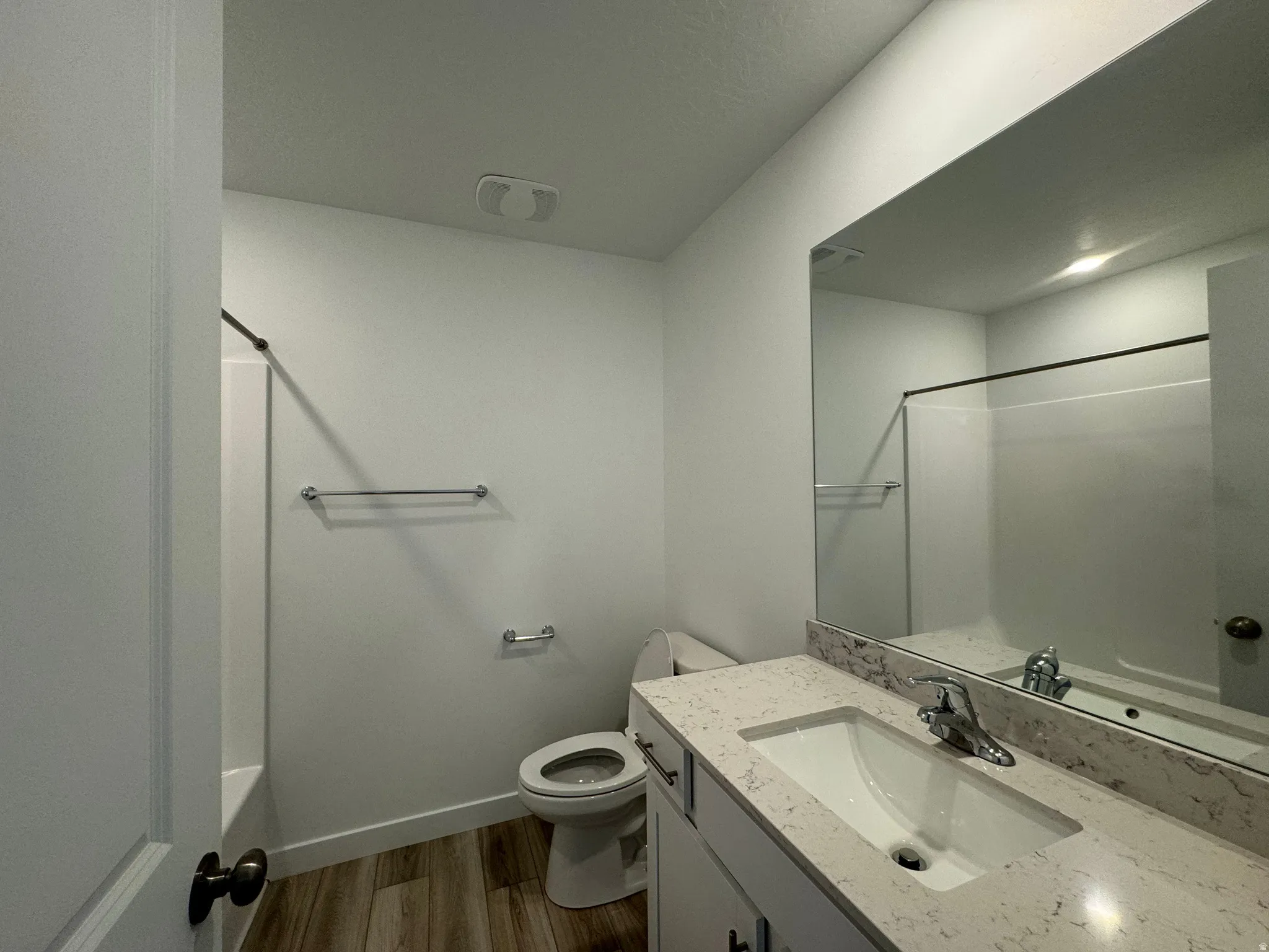 Full bath featuring vanity, dark wood-style floors, and washtub / shower combination