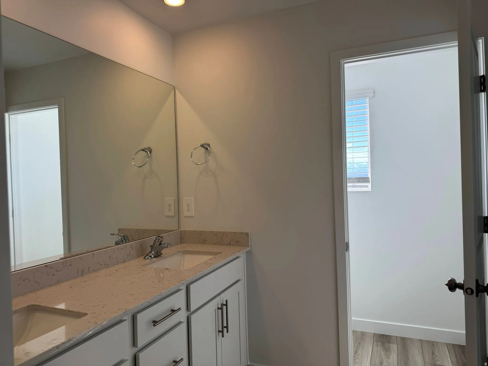 Bathroom with double vanity, light wood finished floors, and recessed lighting