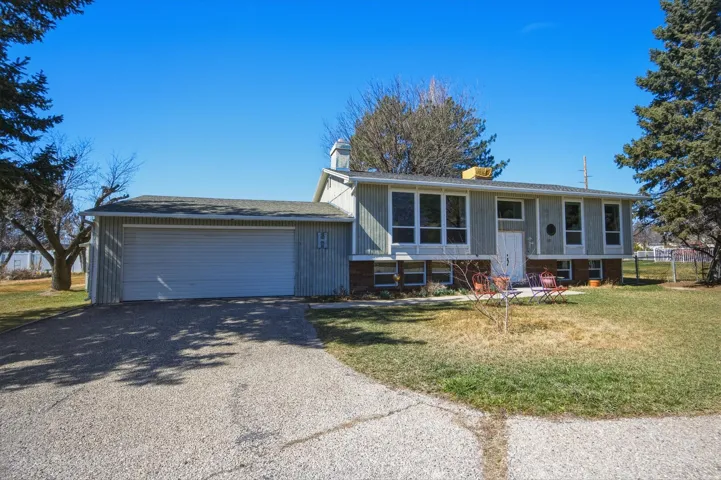 Split foyer home featuring asphalt driveway, a front yard, an attached garage, a chimney, and brick siding