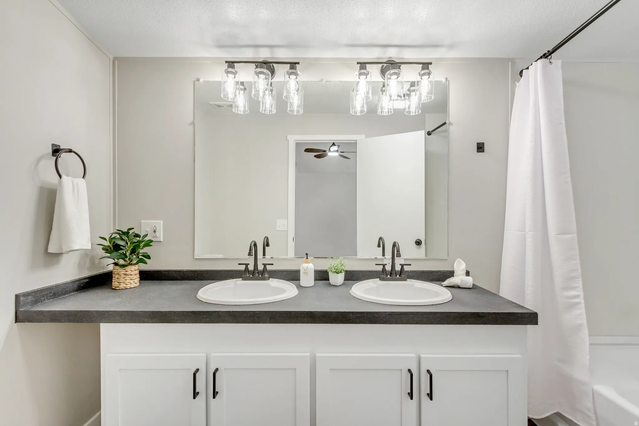 Full bathroom featuring double vanity, ceiling fan, and shower / bath combination with curtain