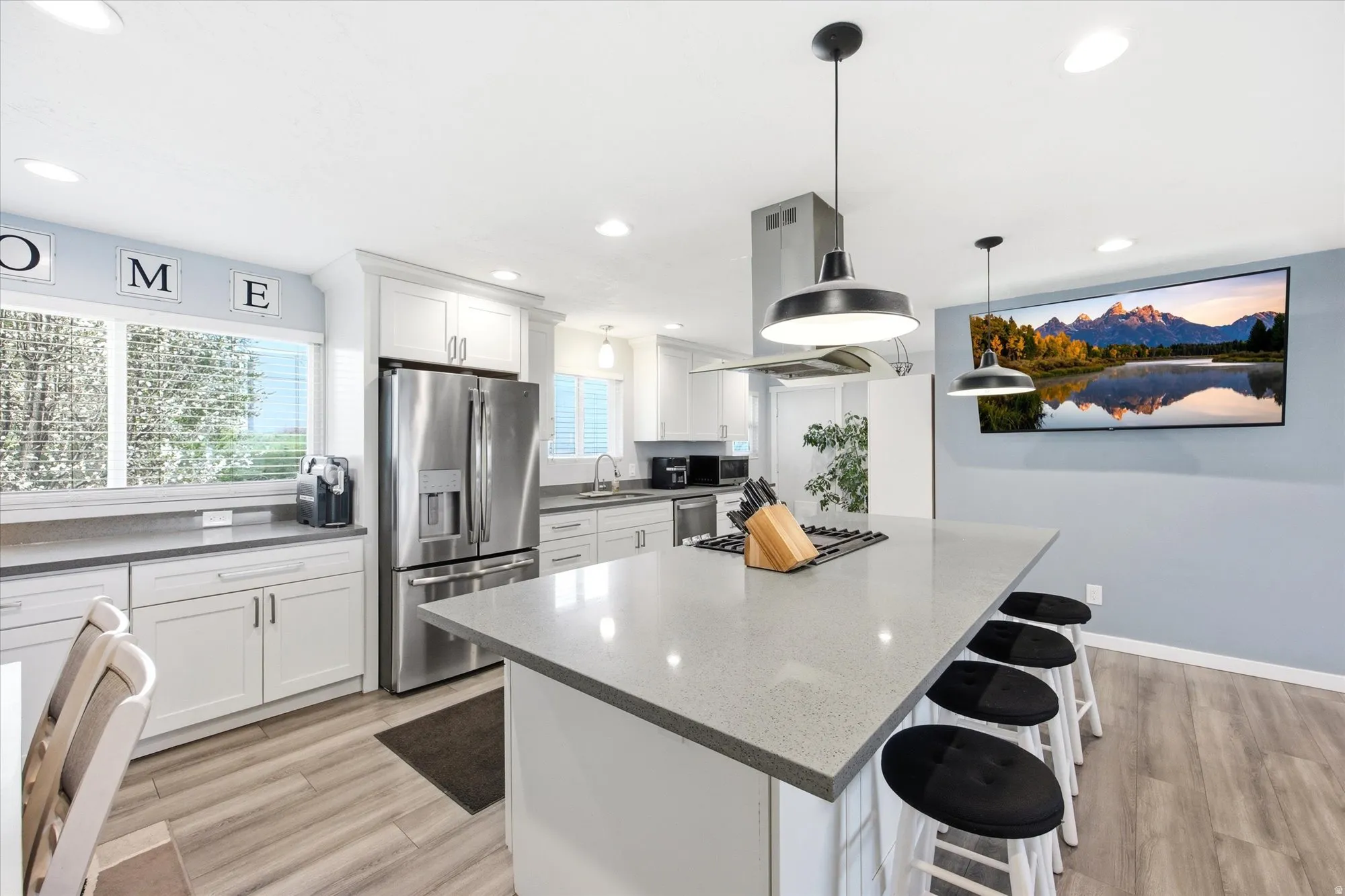 Kitchen with a breakfast bar, white cabinetry, light wood-type flooring, and stainless steel appliances